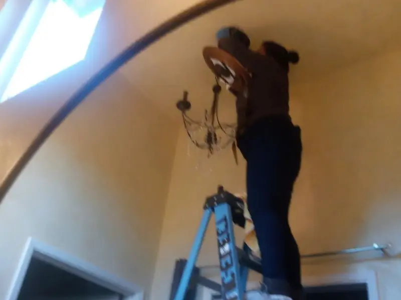 Electrician installing a chandelier in a Stallings residence